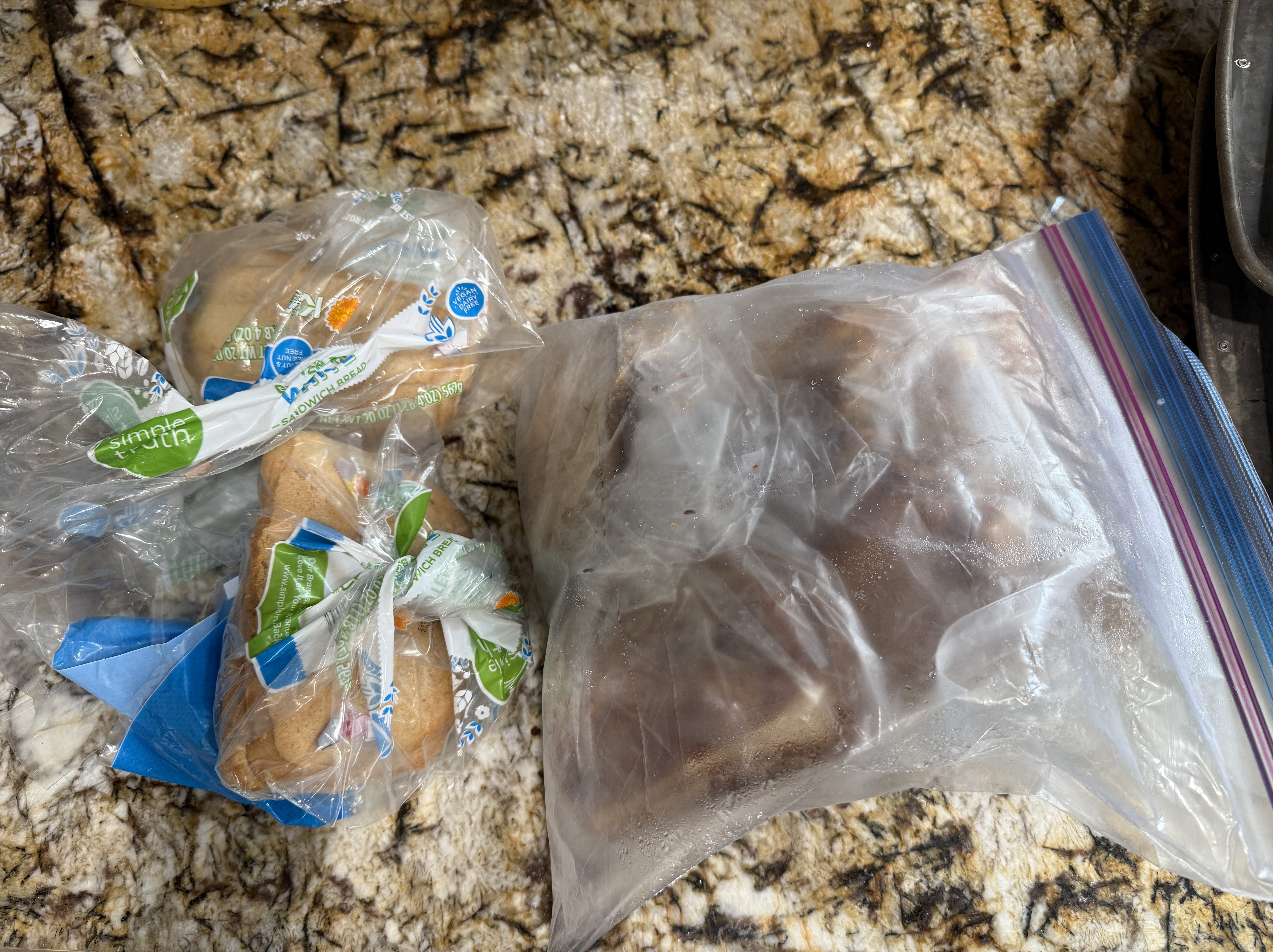 A collection of two bags of bread and frozen items on a countertop, showcasing efforts to minimize food waste.