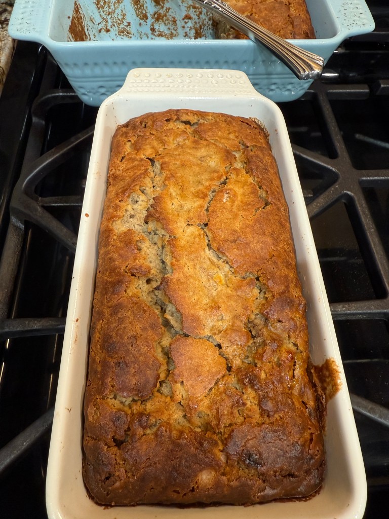 Freshly baked banana bread in a white dish, placed on a stovetop.