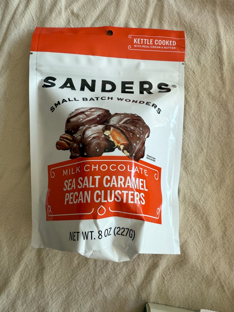 A package of Sanders Milk Chocolate Sea Salt Caramel Pecan Clusters, displayed on a light-colored surface.